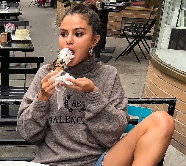 Selena Gomez devours a frozen treat at a sidewalk café as she shows off her legs in Daisy Duke shorts: 'Ice cream chillin'